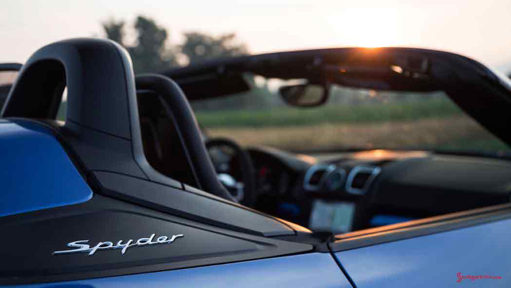 Testing the Boxster Spyder A blue Boxster Spyder is viewed in tight shot at the "Spyder" badging just behind the right door in the fadind Tuscan sun. Credit: Porsche AG