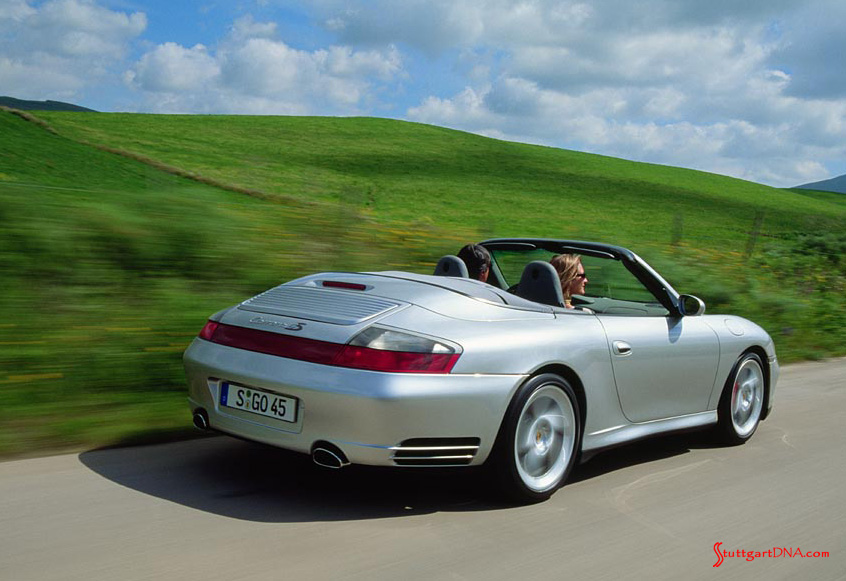 Essential 996-Gen Porsche 911 Buyer Guide by StuttgartDNA 996-gen Porsche 911 Buyer Guide: Seen here is a 996-gen Porsche 911 Carrera 4S arctic-silver Cabriolet, from right-rear angle, at speed on a picturesque country road with a pretty woman in the passenger seat. Credit: Porsche AG