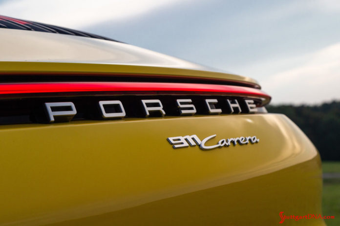Racing Yellow 911 rear badging. Credit: Porsche AG October 2019 USA Sales: This photo is a tight shot of the rear “Porsche 911 Carrera” badging and illuminated continuous red taillight strip on a Racing Yellow 911. Credit: Porsche AG