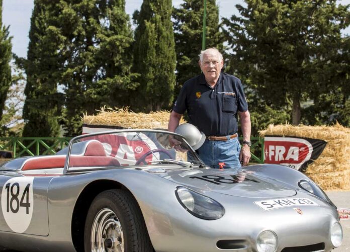Herbert Linge with Porsche 718. Credit: Porsche AG Herbert Linge is seen here posing with a Porsche 718, a racecar he is very familiar with driving and repairing.